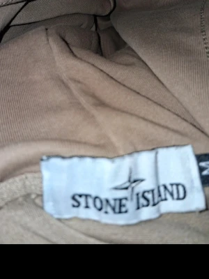  Stone Island hoodie - Säljer en beige hoodie från Stone Island. Hoodien har en klassisk huva och säljer den för vill it ha den