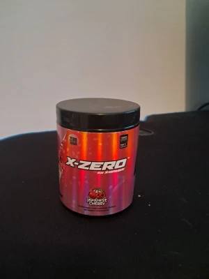 X-Zero Japanese Cherry kosttillskott - Säljer en burk X-Zero kosttillskott med smaken Japanese Cherry. Burken har en snygg röd och svart design och innehåller 160 g pulver, vilket räcker till 100 portioner. Perfekt för dig som tränar och vill boosta din prestation.
