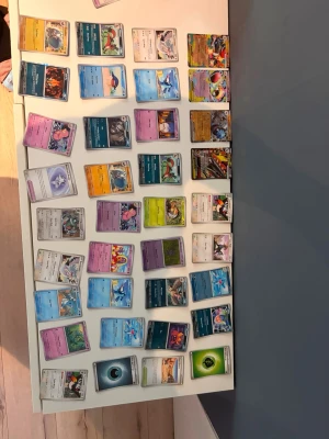 Stor samling Pokémonkort - Säljer en blandad samling Pokémonkort med olika typer, färger och energikort. Perfekt för dig som vill bygga ut din lek eller börja samla. Korten har olika motiv och färger, bland annat blå, lila, gul, orange och grön. Många olika Pokémon och energikort ingår. Antingen som köper du för 20 kr stk eller så kan du få köpa hela boxen för 499