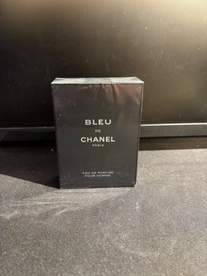 Bleu de Chanel Eau de Parfum - Bleu de Chanel Eau de Parfum är en elegant herrdoft i en stilren, mörkblå rektangulär flaska. Förpackningen har en lyxig känsla med tydlig Chanel-logga och silverfärgad text. Perfekt för dig som gillar exklusiva och maskulina parfymer.