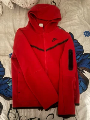 Röd Nike tech hoddie - En jätte snygg röd Nike tech köp ifrån JD sports.💕 Jätte mjuk och bekväm att ha på sig vart som helst!💕Passar dig som har storlek XS och kan även passa S.💕 finns små tecken på användning men annars är det nästan som ny!💕