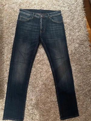 Dsquared Jeans - Snygga mörkblå Dsquared 2 jeans med raka ben och klassisk femficksmodell. Jeansen har subtila slitningar framtill och bakfickor utan dekorationer. Tillverkade i denim med en skön passform, perfekta till vardagslooken.