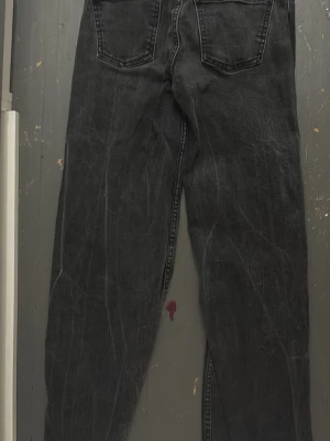 Svarta raka jeans med tvättad look - Säljer ett par svarta jeans med rak passform och tvättad, lite sliten look. Jeansen har klassiska bakfickor och framfickor samt normal midja. Materialet är denim i bomull och färgen är en snygg urtvättad svart.