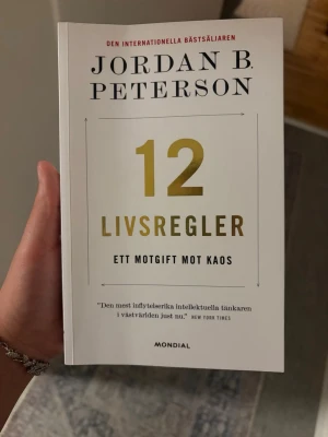 12 livsregler av Jordan B. Peterson - En internationell bästsäljare av Jordan B. Peterson. Boken har vit framsida med guldfärgad text och svart tryck. Den tar upp 12 praktiska och djupgående livsregler som utmanar och inspirerar till reflektion kring vetenskap, tro och mänsklig natur. Utgiven av Mondial.