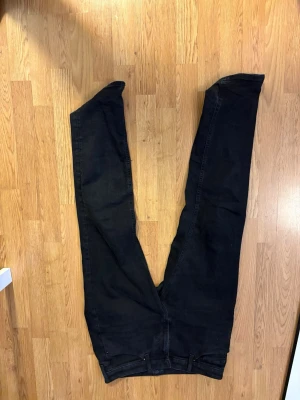 Svarta slim fit jeans Jack and Jones - Säljer ett par svarta slim fit jeans med klassisk femficksdesign och normal midja. Jeansen har raka ben och är tillverkade i ett mjukt denimtyg med lite stretch för extra komfort. Perfekta för dig som gillar en enkel och stilren look.
