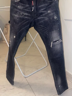 Dsquared2 jeans grå - Dsquared2 jeans i storlek 48, givetvis äkta! Köpta 2021 på Ranwald i Halmstad. Jeansen är grå/svarta med rött färgstänk. (Nyskick)