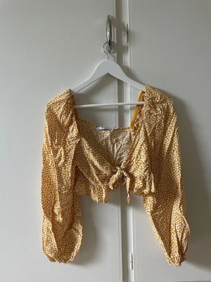 Crop topp - Gul croptop med vita blommor. Knyts framtill. Fint skick! 