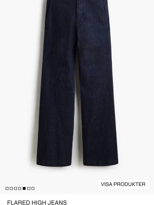 Mörkblå flared jeans med hög midja - Säljer ett par mörkblå flared jeans med hög midja och vida ben. Jeansen har diskreta bakfickor utan synliga sömmar och är tillverkade i ett klassiskt denimtyg. Perfekta för dig som gillar en trendig siluett och vill ha ett par stilrena jeans. använt 1 gånge, skriv för fler bilder