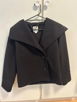 Svart kort kappa - Super snygg kort kappa ifrån Gina Tricot. Har använts få tal gånger. Den är I barnstorlek 158/164 men jag skulle säga att den passar som en XS. Köpte ny för 500kr.