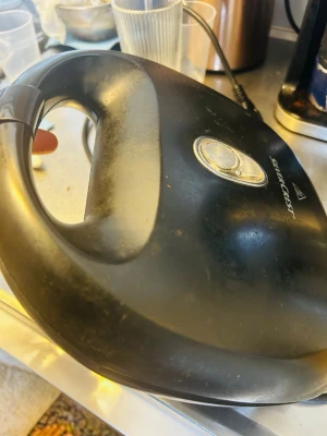 Svart smörgåsgrill SilverCrest - En svart smörgåsgrill från SilverCrest med rundad form och bärhandtag. Grillen har indikatorlampa på ovansidan och är tillverkad i plast och metall. Perfekt för att snabbt fixa varma mackor hemma.