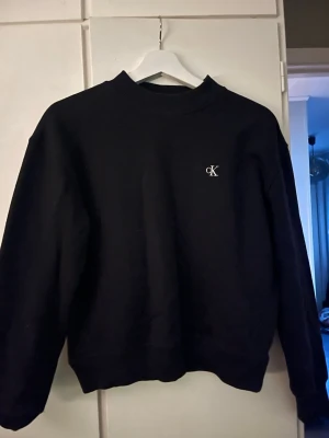 Svart Calvin Klein Jeans sweatshirt - Säljer en svart sweatshirt från Calvin Klein Jeans med CK-logga på bröstet. Använd men väldigt fint skick.