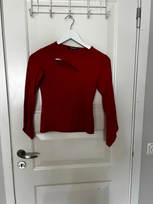 Röd långärmad topp med cut out - Trendig röd långärmad topp med en snygg cut out-detalj vid halsen. Toppen har en slim passform och är perfekt för dig som vill sticka ut lite extra. Tillverkad i ett mjukt och stretchigt material som sitter skönt på kroppen.