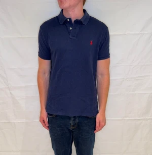 Polo Ralph Lauren Slim Fit Polo - Slim fit pikétröja i marinblått, 100% bomull, pre-owned i mycket gott skick.