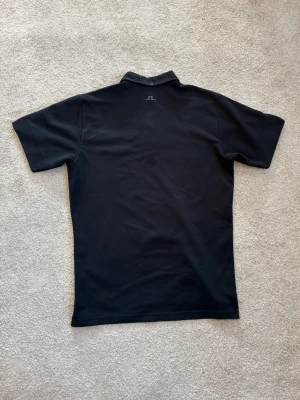 J.Lindeberg piké - Svart J Lindeberg piké i grymt härligt material, luftig och perfekt för en golfdag och i väldigt fint skick, säljer då den inte kommer till användning:)
