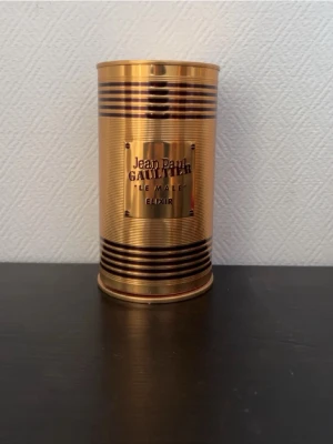 Jean Paul Gaultier Le Male Elixir - Lyxig parfym från Jean Paul Gaultier, Le Male Elixir. Flaskan har en unik guldfärgad design i form av en manlig torso med metalliska ränder och matchande guldfärgat metallhölje. Perfekt för dig som gillar exklusiva och iögonfallande dofter.