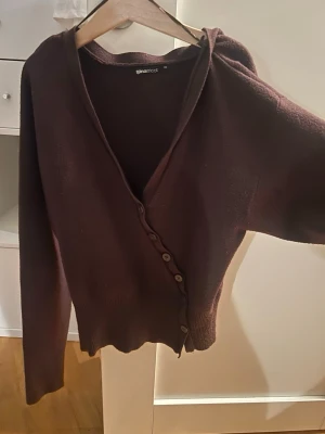 Brun kofta från Gina Tricot - Mysig brun kofta från Gina Tricot med v-ringning och knappar framtill. Långärmad modell i mjukt stickat material, perfekt att slänga över en topp eller t-shirt. Enkel och stilren design som passar till det mesta.