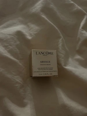Lancôme Absolue ögonkräm 5 ml - Lyxig ögonkräm från Lancôme i serien Absolue. Kommer i en liten, beige kartong på 5 ml. Innehåller extrakt av evighetsros och är framtagen för att revitalisera huden runt ögonen. Perfekt för dig som vill boosta din hudvårdsrutin.
