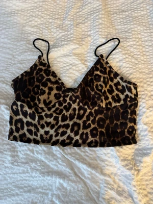 Leopardmönstrad linnetopp från SHEIN - Snygg leopardmönstrad linnetopp från SHEIN med tunna svarta axelband och v-ringad hals. Toppen har en croppad passform och är perfekt för dig som vill sticka ut med ett djurmönster. Materialet är mjukt och stretchigt för en bekväm känsla.