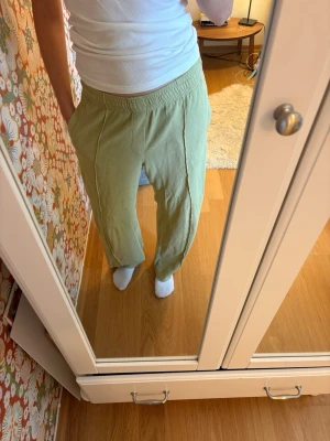 Ljusa gröna mjukisbyxor med resår weekday - Säljer ett par ljusgröna mjukisbyxor med avslappnad passform och resår i midjan. Byxorna har raka ben och synliga sömmar framtill som ger en cool detalj.
