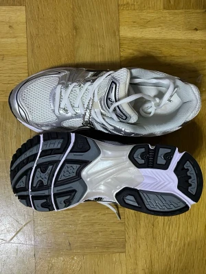 asics gel kayano 14 - Snygga vita Asics sneakers med silvriga och svarta detaljer. Ovandelen är i mesh och syntet för bra andningsförmåga och komfort. Klassisk Asics-logga på sidan och rejäl sula med svart och grått mönster för bra grepp. Perfekta för en sportig look.