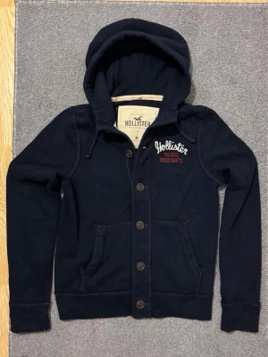 Vintage Hollister Cardigan Med Knappar - Säljer denna otroliga sällsynta och feta Hollister cardigan med knappar | Mycket bra skick | Längd ≈ 65 cm, Bredd armhåla–armhåla ≈ 52 cm | Jag är 184 cm, 70 kg.