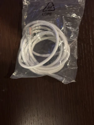 Vit nätverkskabel  - En vit nätverkskabel med RJ45-kontakter, levereras i en genomskinlig plastpåse. Kabeln är rund och flexibel, perfekt för att koppla ihop datorer eller annan elektronik med nätverk. Passar till de flesta standardutrustningar inom elektronik.