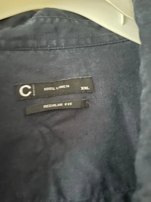 Mörkblå linneskjorta regular fit - Snygg mörkblå skjorta i 100% linne med regular fit. Skjortan har långa ärmar och klassisk krage, perfekt för en avslappnad men stilren look. Knappstängning framtill och vid ärmsluten.