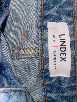 Ljusblå jeansshorts med fransig kant - Säljer ett par ljusblå jeans i klassisk denim med snygg rå och fransig kant nertill. Jeansen har en avslappnad vibe och är perfekta för dig som gillar en trendig och lite edgy stil. Materialet är 100% bomull och färgen är riktigt fräsch ljusblå. Dem har skador nere vid baksidorna då dem hamnat under skorna 