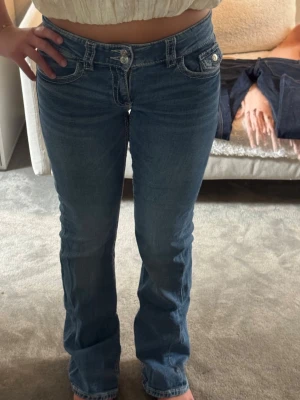 Blå bootcut jeans med låg midja - Säljer ett par super fina blå bootcut jeans med låg midja och dubbla knappar fram. 