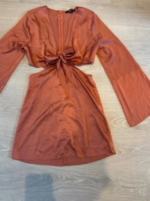 Kort omlottklänning i satin med rosett - Snygg kort klänning i korall färg