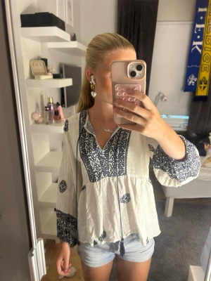 Vit Zara blus med blått mönster - Säljer en luftig vit blus med blått mönster och v-ringning, så fin till sommaren och passar till både jeans och shorts, säljer för att den inte kommer till användning❣️❣️