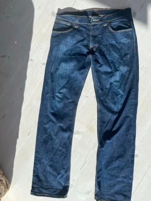 Mörkblå nudie jeans straight fit - Snygga straight fit nudie jeans i en mörkblå färg med snygg tvätt  Storlek: W34 L32  Modell: Average Joe straight fit  Saknas en knapp