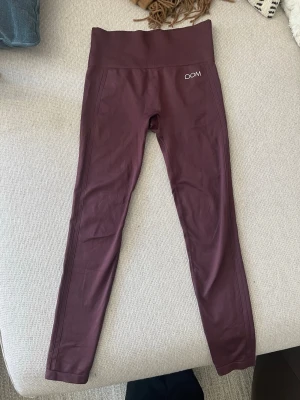 Vinröda leggings från Drop of Mindfulness - Snygga vinröda leggings från Drop of Mindfulness med hög midja och stretchigt material. Perfekta för träning eller chill. Diskret logga på höften och bred linning för extra komfort.