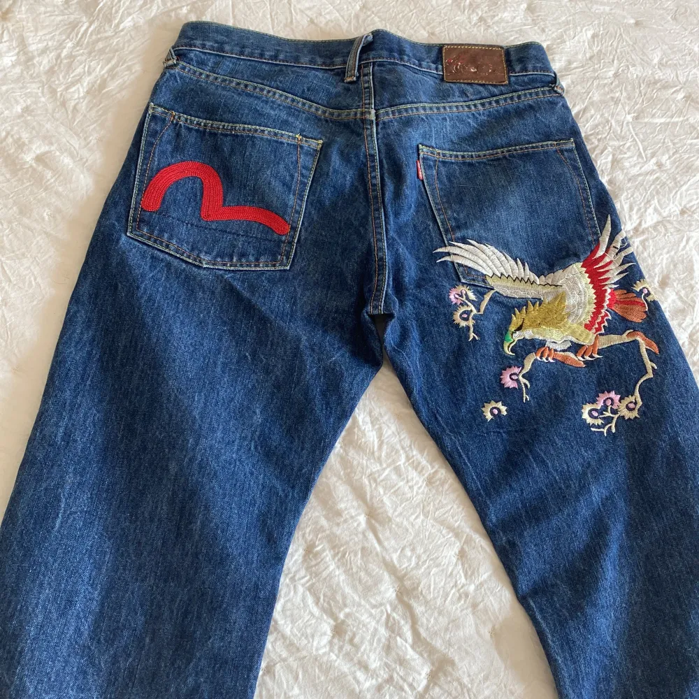 Säljer ett par evisu jeans i storlek 34 med rött motiv( se bild ) Längd från midja till benslut 96 cm. Midjemått tvärs över 43 cm. Benöppning 21 cm. Gott skick! ✨. Jeans & Byxor.