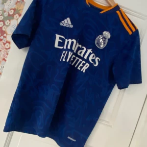 Real Madrid 2021/2022 borta ställ - Köptes för ungefär ett år sedan. Mycket bra skick men några slitningar vid halsen. Skriv privat för fler funderingar. 