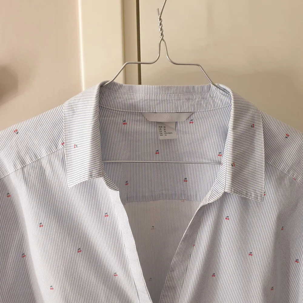 Ljusblå randig skjorta med små körsbär från H&M. Aldrig använts. Storlek 46, men passar mer som en 42/44. Skönt strechigt material . Skjortor.