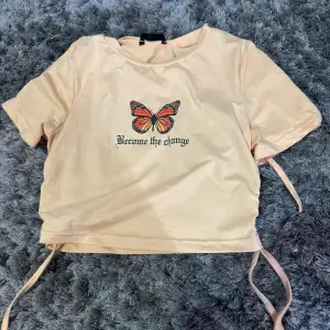 Ljusgul T-shirt med fjärils tryck med drapering på sidorna! Storlek S