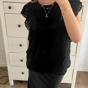 Svart topp  - Jag säljer en svart topp med lite spets. Toppen har fina armar med lite som volanger. Toppen är i fint sick och knappt använd. Säljer för att den inte kommer till någon användning😇