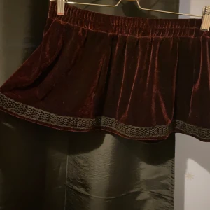 Mörkröd ultra mini skirt - Röd minikjol i sammet(?) köpt på läkarmissionen, var från början medellång men sydde om den och la till spetsband. Väldigt kort på mig (163 cm)