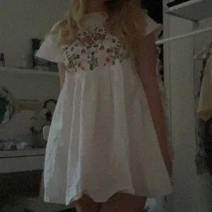 Kort klänning - Vit kort klänning prydd med broderade blommor. Verkligen supersöt och somrig!! Den är tidigare köpt på Sellpy, för 130kr, men är fint bevarad. Skriv gärna vid eventuella frågor 💞