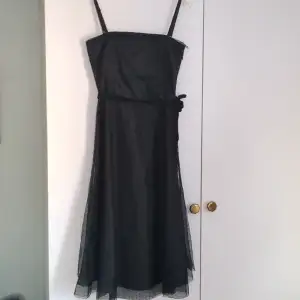 Vacker svart klänning med spets. Snöret är lite trasigt på ett ställe men syns knappt. Annars i nyskick.
