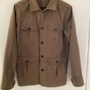 Oscar Jacobsson Safari jacka  - Oscar Jacobsson Safari jacka i grön. Säljer eftersom inte används längre. Bara använd en säsong och mycket fint skick, inga defekter förutom flärpen inne i jackan(bild finns med). Kontakta för eventuella frågor . Nypris 1800, mitt pris 950. Storlek S