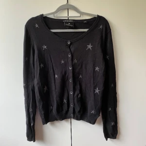 Maison Scotch svart kofta med stjärnor  - Svart kofta med silvriga stjärnor fån märket Maison Scotch.  Storleken är 4 vilket skulle motsvara en S/M