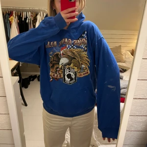 Blå vintage hoodie med tryck  - Blå vintage hoodie med tryck i strl L, fint skick förutom en fläck på armen (se bild 1).   Jag säljer just nu över 15 st liknande vintagetröjor så kolla min profil för fler, skriv vid frågor!!