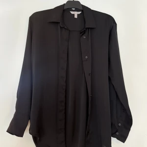 Svart blus  - Oversize blus/skjorta i glansigt material.