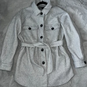 Mjuk kappa - Går över halva rumpan. Knappar samt knyte. Fickor vid bröstet samt sidorna. Mycket fint skick. 