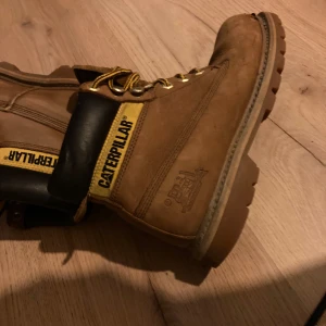 Bruna kängor från Caterpillar - Ett par bruna kängor från Caterpillar med snörning och svarta detaljer. Skorna har en kraftig sula och är designade för att vara slitstarka och bekväma.. stl 38 ! knappt använda.
