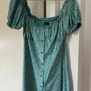 Blommig klänning - Blommig klänning med puffärm, knappar längst med hela framsidan