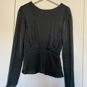 Svart blus - Svart blus med öppen rygg samt resår vid midjan. Storlek 36 från NAKD men skulle säga att den passar som 38 också