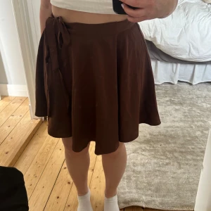 Superfin kjol - Jättefin brun volangkjol som man knyter omlott. Endast använd Max 3 gånger så nyskick! En liten blekingsfläck på bandet man knyter men annars superfint skick!